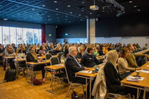 Bilde av konferanse med mange tilhørere